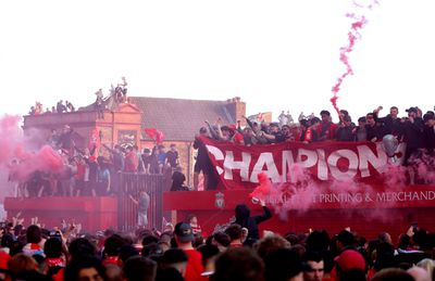 Fans of Liverpool hold up a banner which reads “Champions”, while standing on top of a merchandise stand and wave smoke flares, as they celebrate the teams victory and confirmation of winning the Premier League title, outside of the stadium after the Premier League match between Liverpool FC and Tottenham Hotspur FC at Anfield on April 27, 2025 in Liverpool, England.